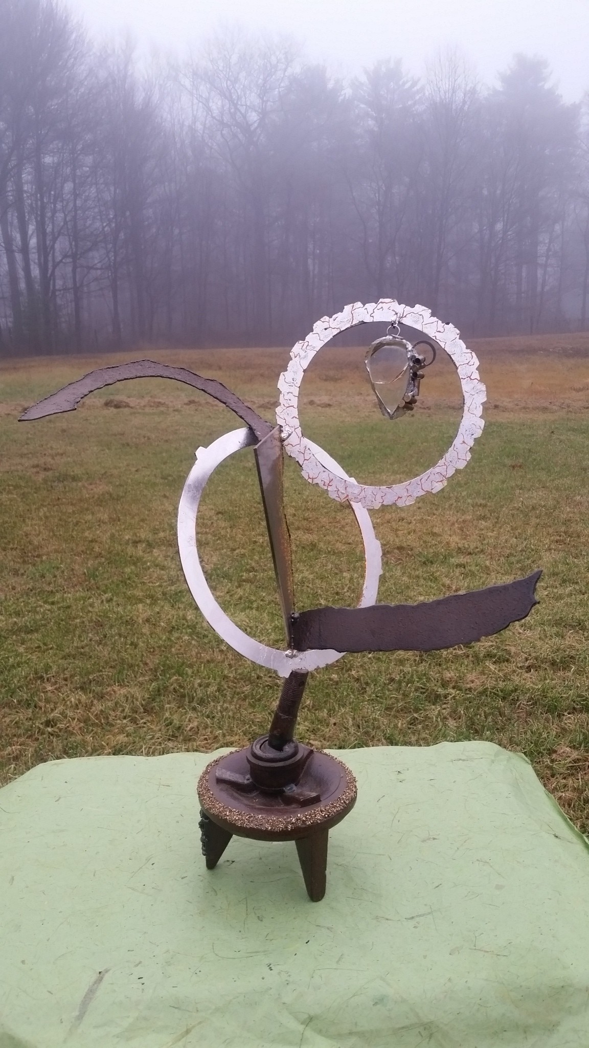 Welded metal sculpture with brass chips and glass, finished in silver leaf and paint. Amulet is a piece of jewelry to be worn.